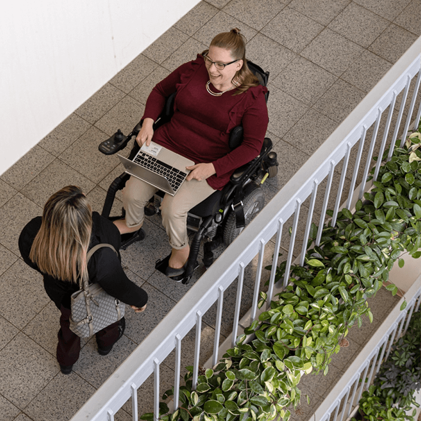 Two women with disabilities on balcony talking
